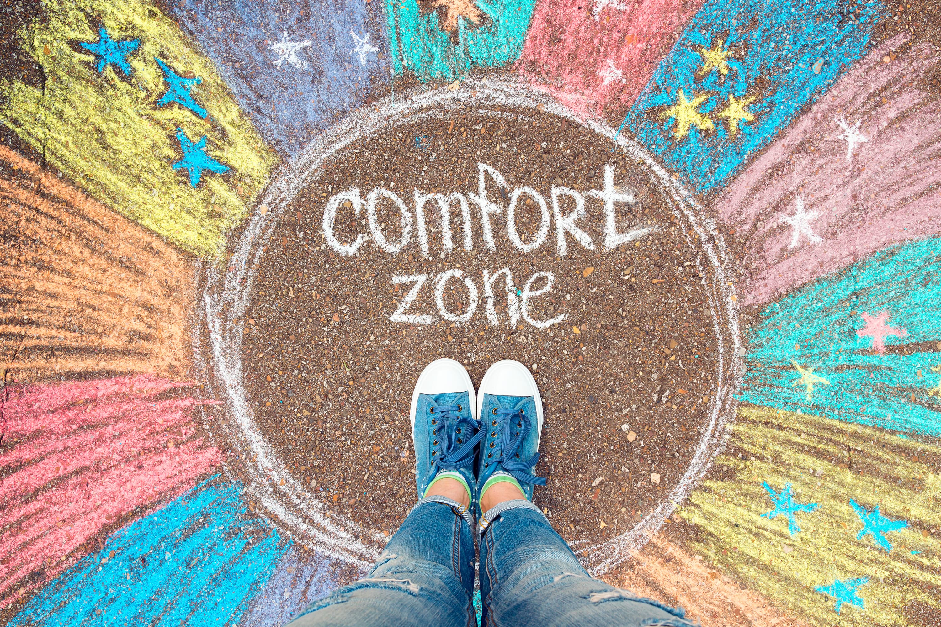 close up of a persons feet in sneakers standing inside a chalk circle labelled comfort zone